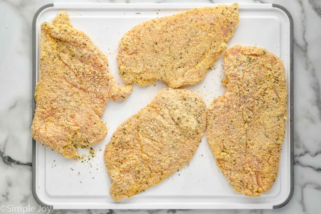 overhead of breaded chicken cutlets on a cutting board to make Chicken Parmesan