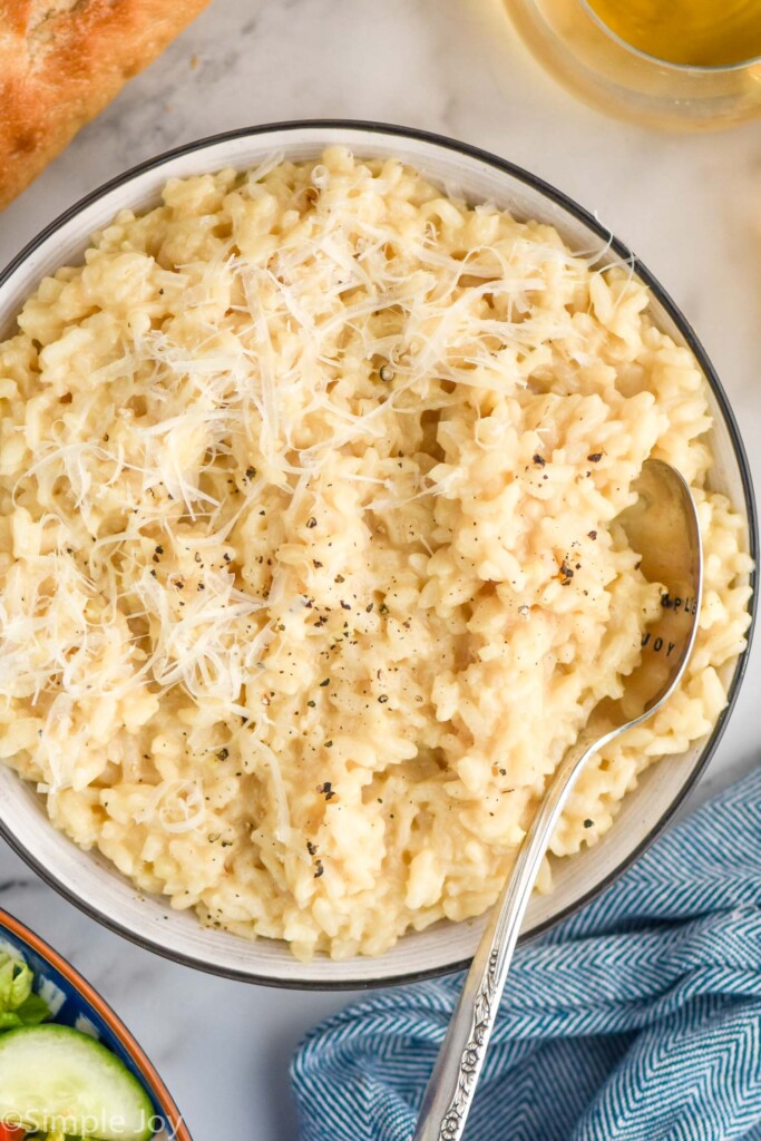 overhead of bowl of Instant Pot Risotto toped with black pepper and parmesan cheese with spoon in bowl