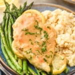 Plate of Lemon Chicken topped with parsley, rissoto, and asparugus