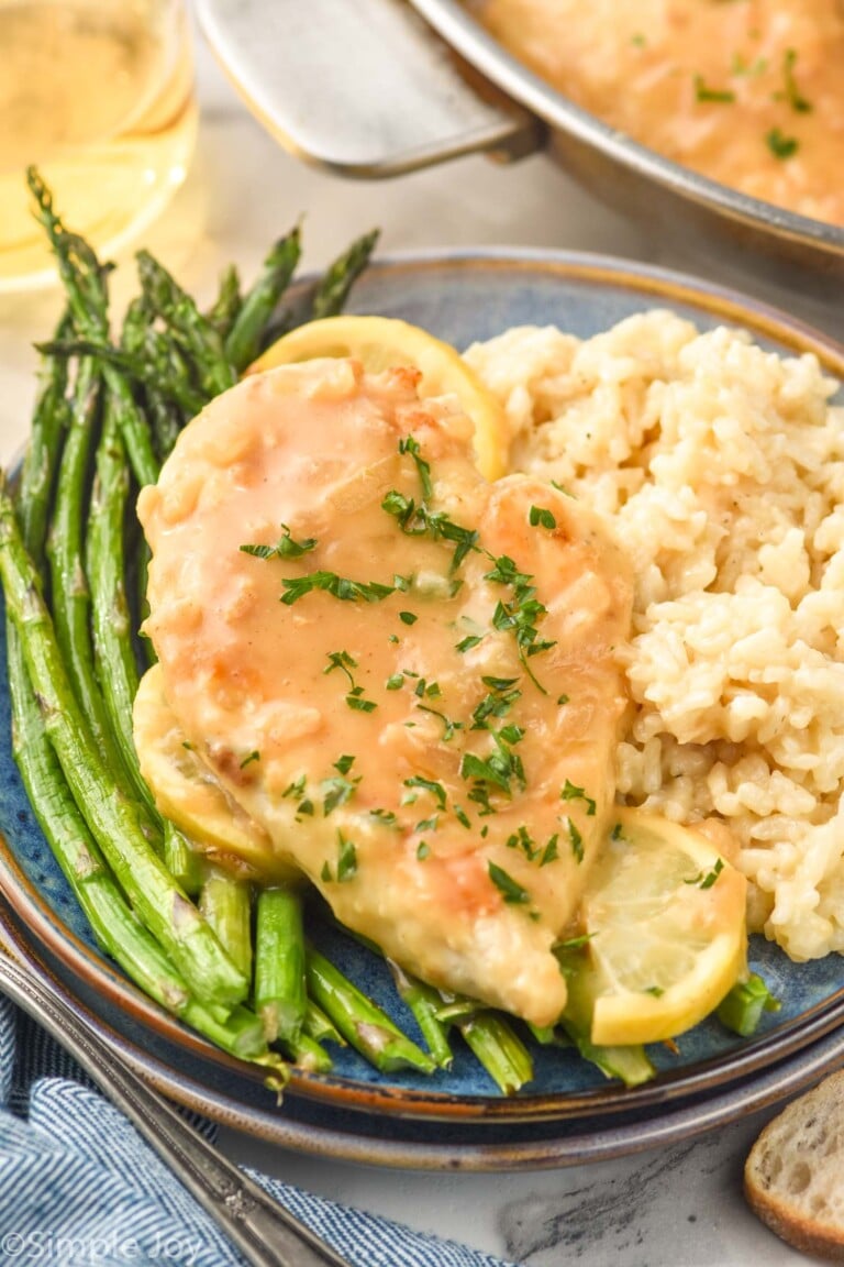 Plate of Lemon Chicken topped with parsley, rissoto, and asparugus