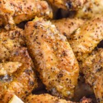 close up of lemon pepper wings with lemon slice sitting in front