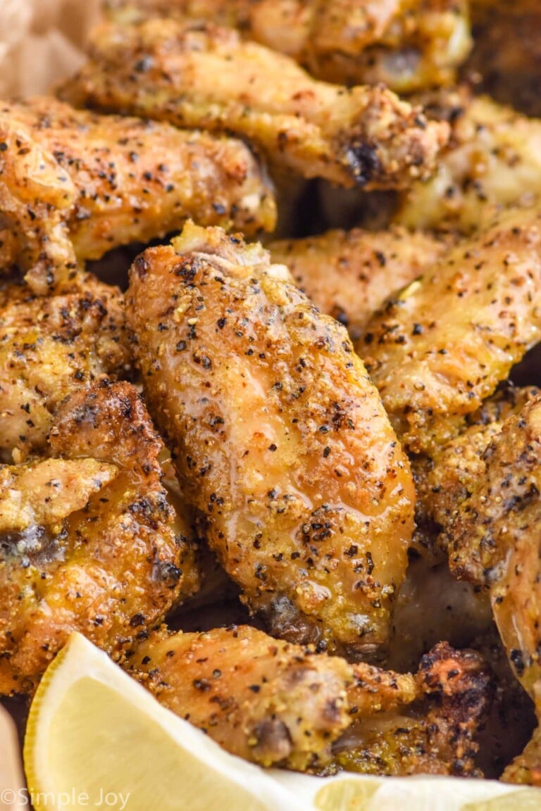 close up of lemon pepper wings with lemon slice sitting in front