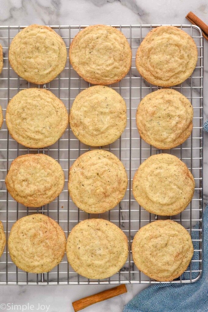 overhead of Chai Sugar Cookies on a wire cooling rack. Two cinnamon sticks sitting beside