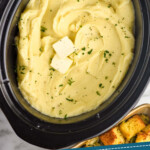 Pinterest graphic for crockpot mashed potatoes. Image shows overhead of crockpot of crockpot mashed potatoes topped with butter and fresh parsley. Says "crockpot mashed potatoes simplejoy.com"