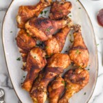 overhead of platter of Oven Baked Chicken Legs with bowl of bbq sauce sitting beside