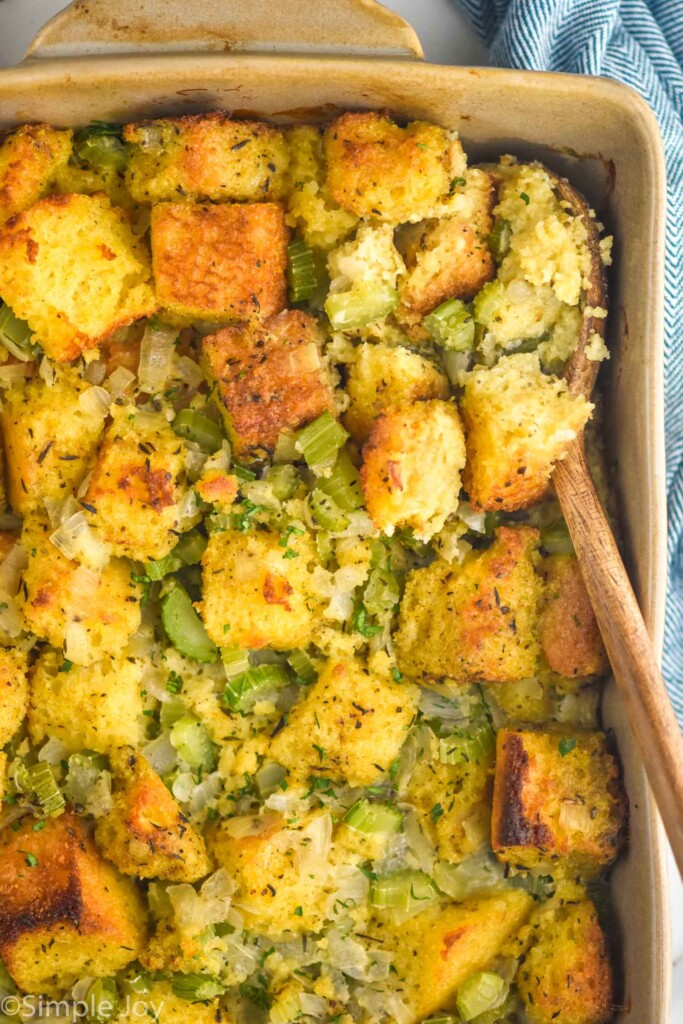 Close up of baking pan of Cornbread Stuffing with a wooden spoon for serving