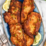 overhead of platter of crispy chicken cutlets with lemon wedges sitting beside