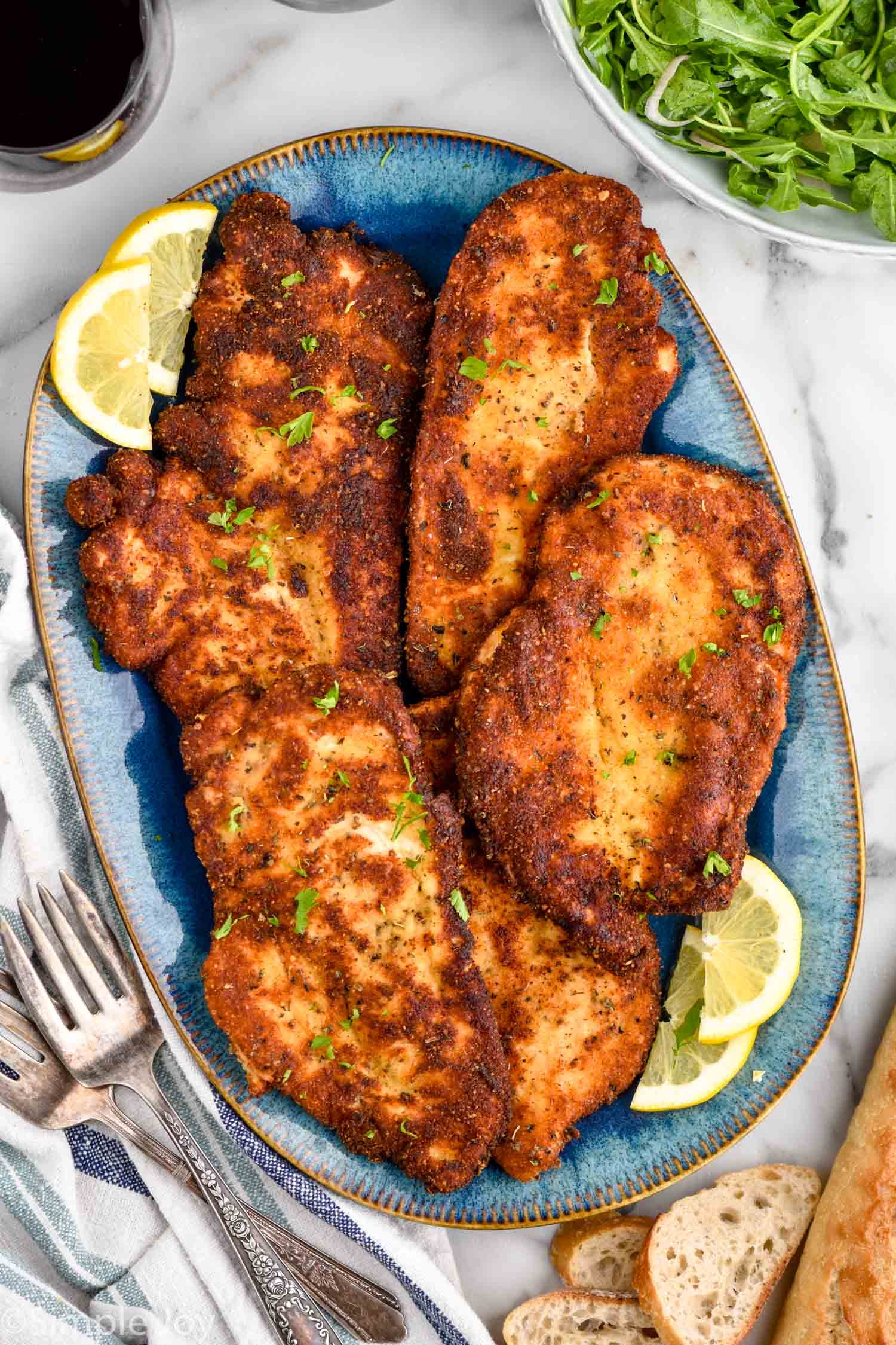 overhead of platter of crispy chicken cutlets with lemon wedges sitting beside