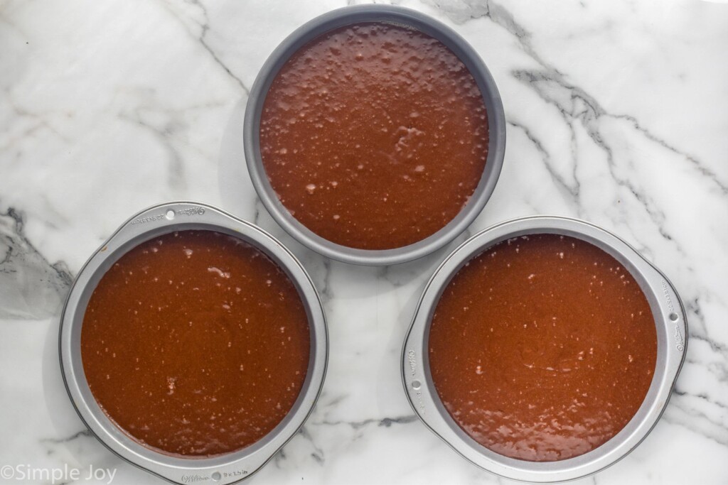 chocolate cake batter in three cake pans before baking