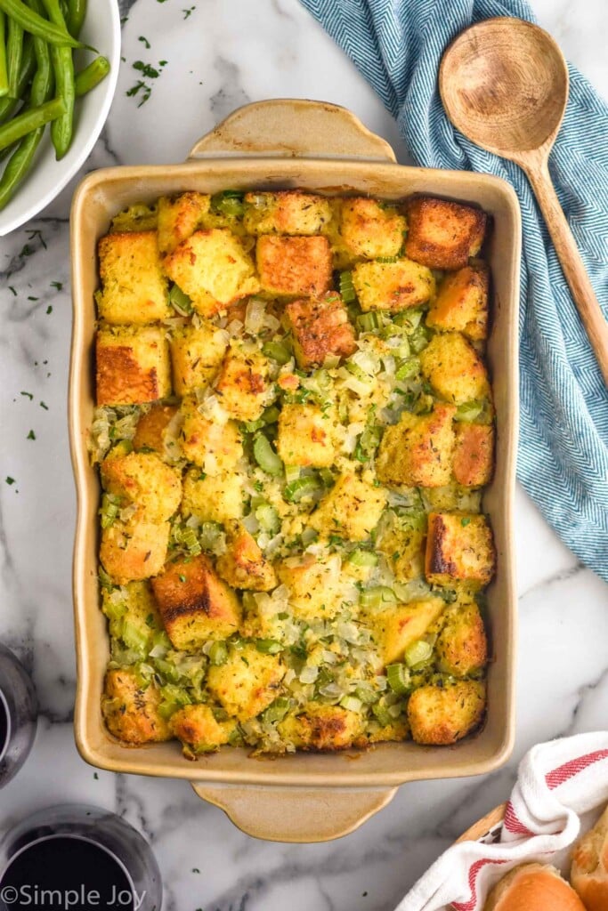 overhead of casserole dish of Cornbread Stuffing with wooden spoon sitting beside