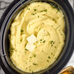 overhead of crockpot of crockpot mashed potatoes mashed potatoes topped with butter and fresh parsley