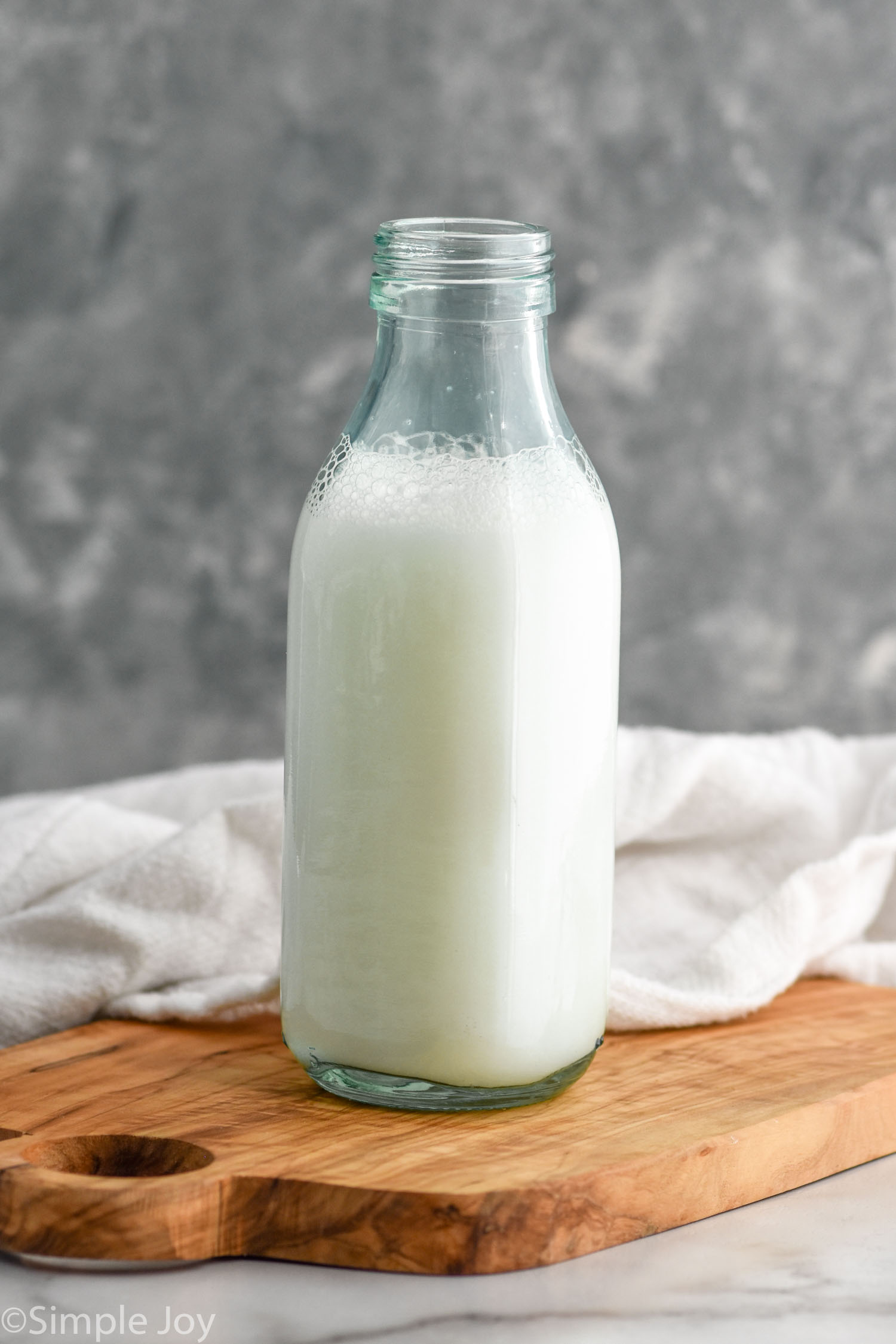 Glass bottle of Homemade Buttermilk sitting on a wooden board