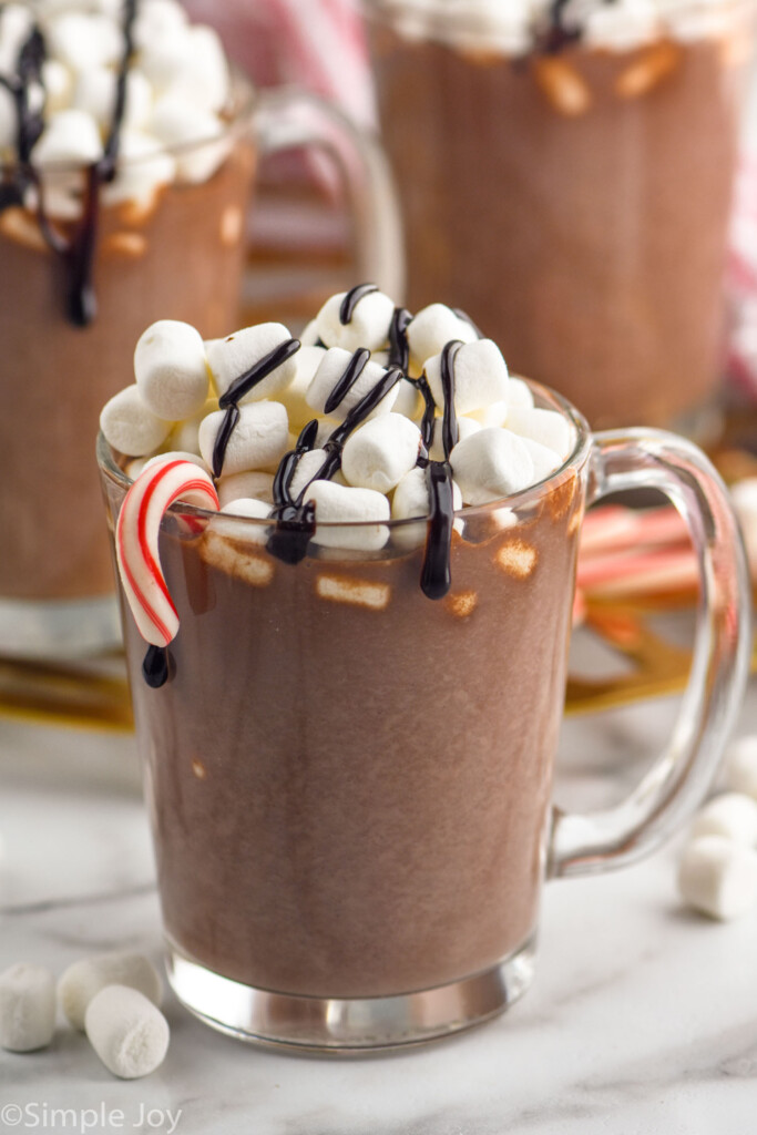 Mug of homemade Hot Chocolate topped with marshmallows and chocolate sauce with candy cane