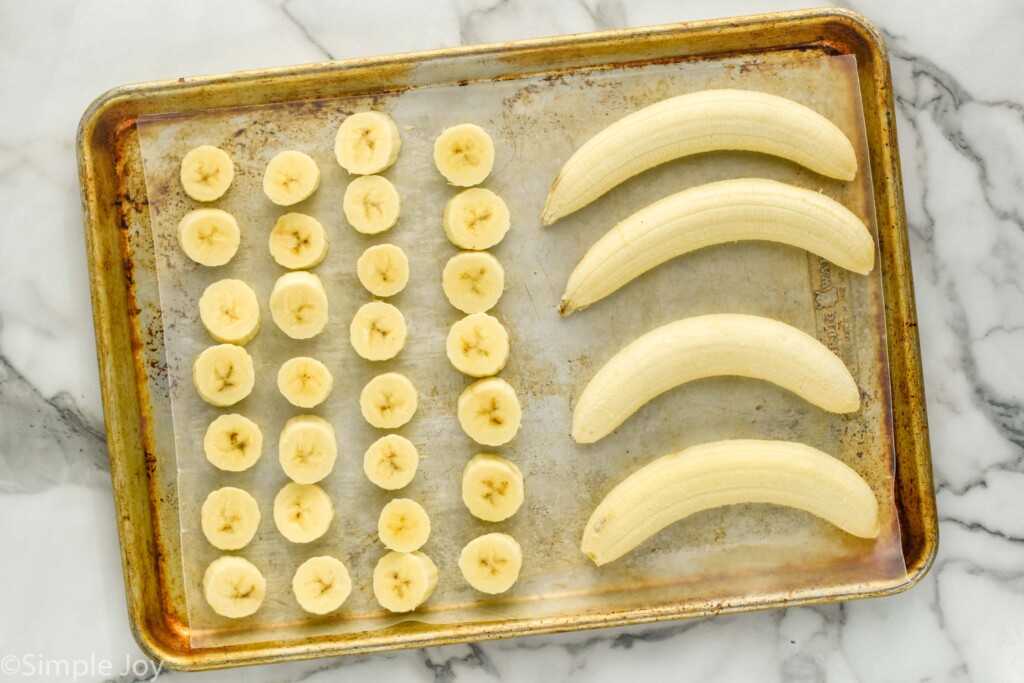 overhead of rimmed baking sheet of peeled and sliced bananas on wax paper to show How to Freeze Bananas