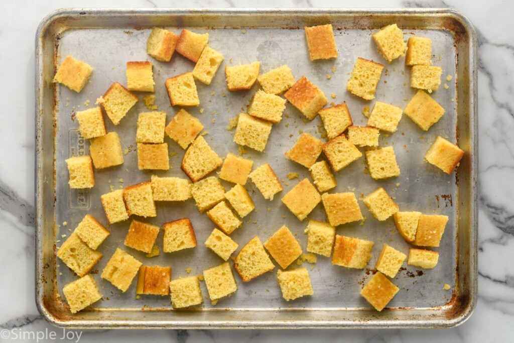 overhead of rimmed baking sheet with cubed cornbread to make Cornbread Stuffing