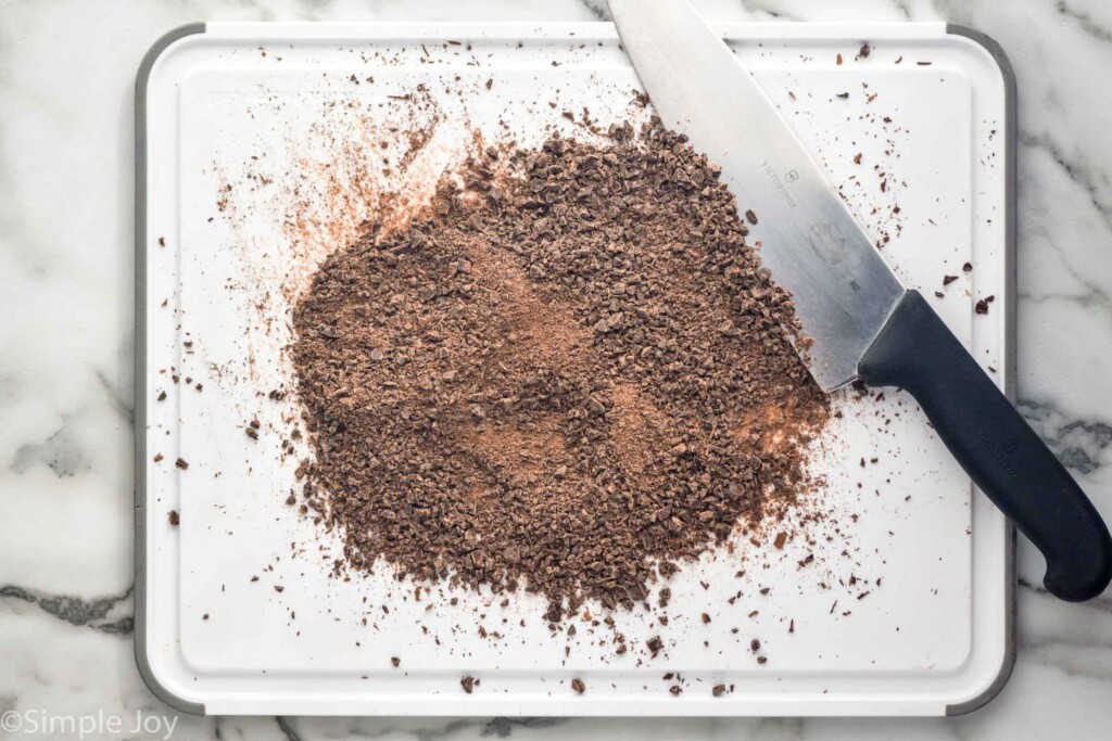 overhead of cutting board with chocolate that has been chopped for homemade Hot Chocolate with a knife sitting beside