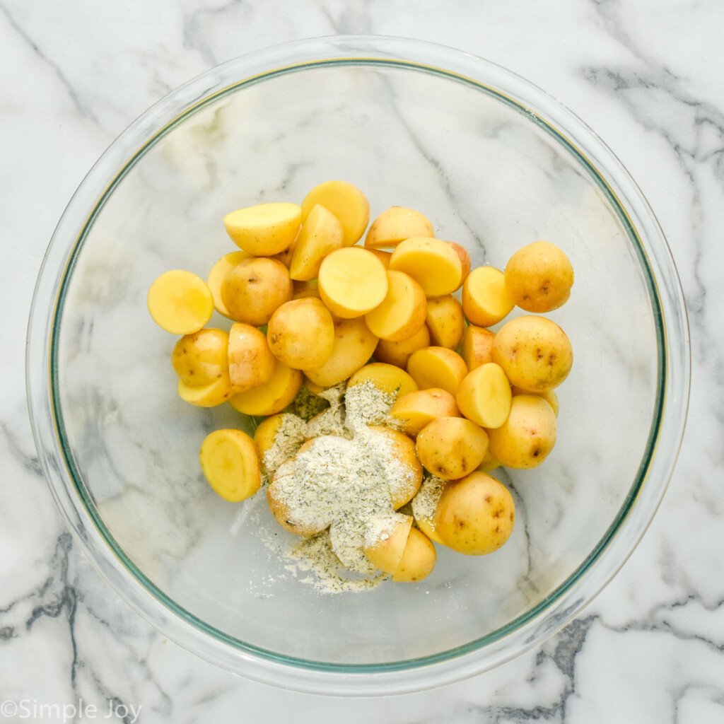 overhead of glass bowl of cut potatoes with ranch seasoning to make Ranch Potatoes