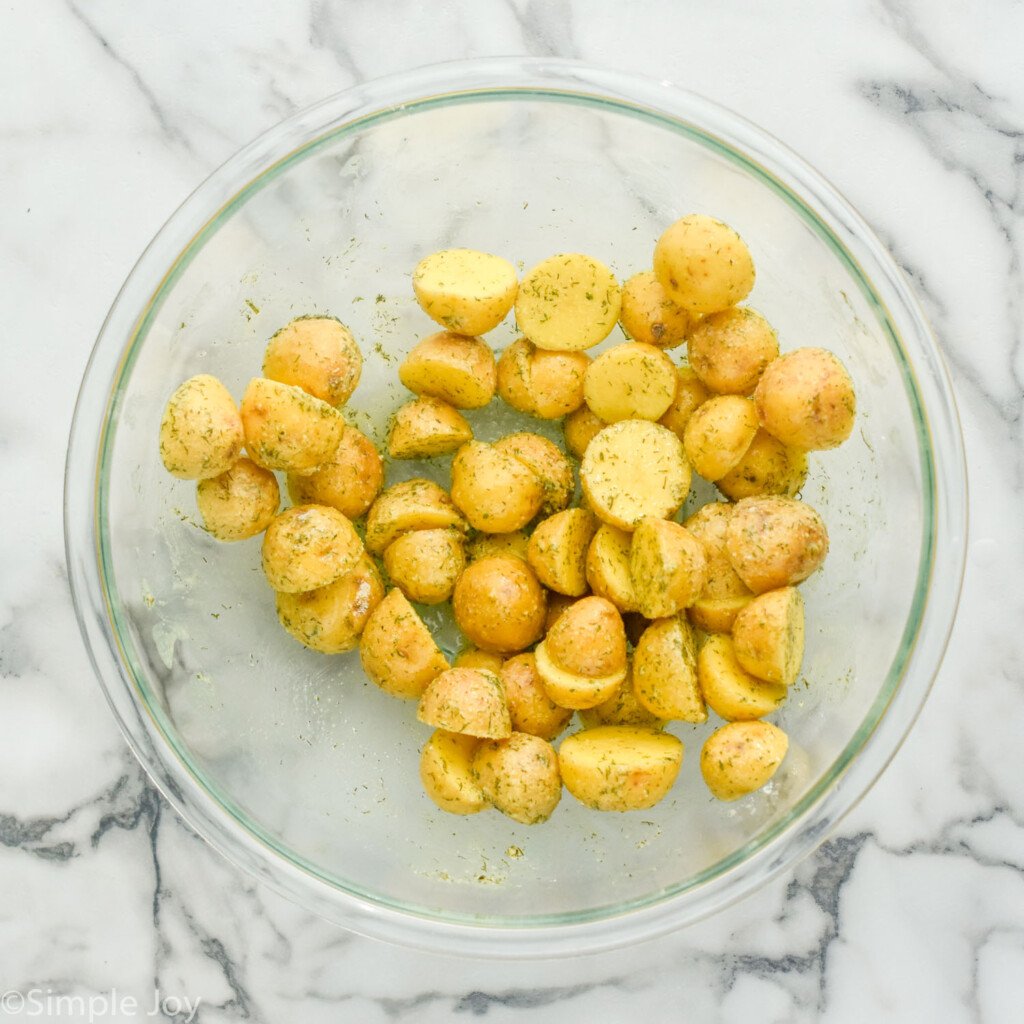 overhead of glass bowl of halved little yellow potatoes with ranch seasoning to make Ranch Potatoes