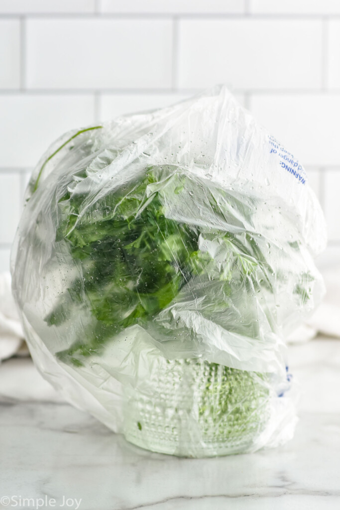 fresh parsley in a drinking glass with water and a plastic bag over it to show How to Store Parsley