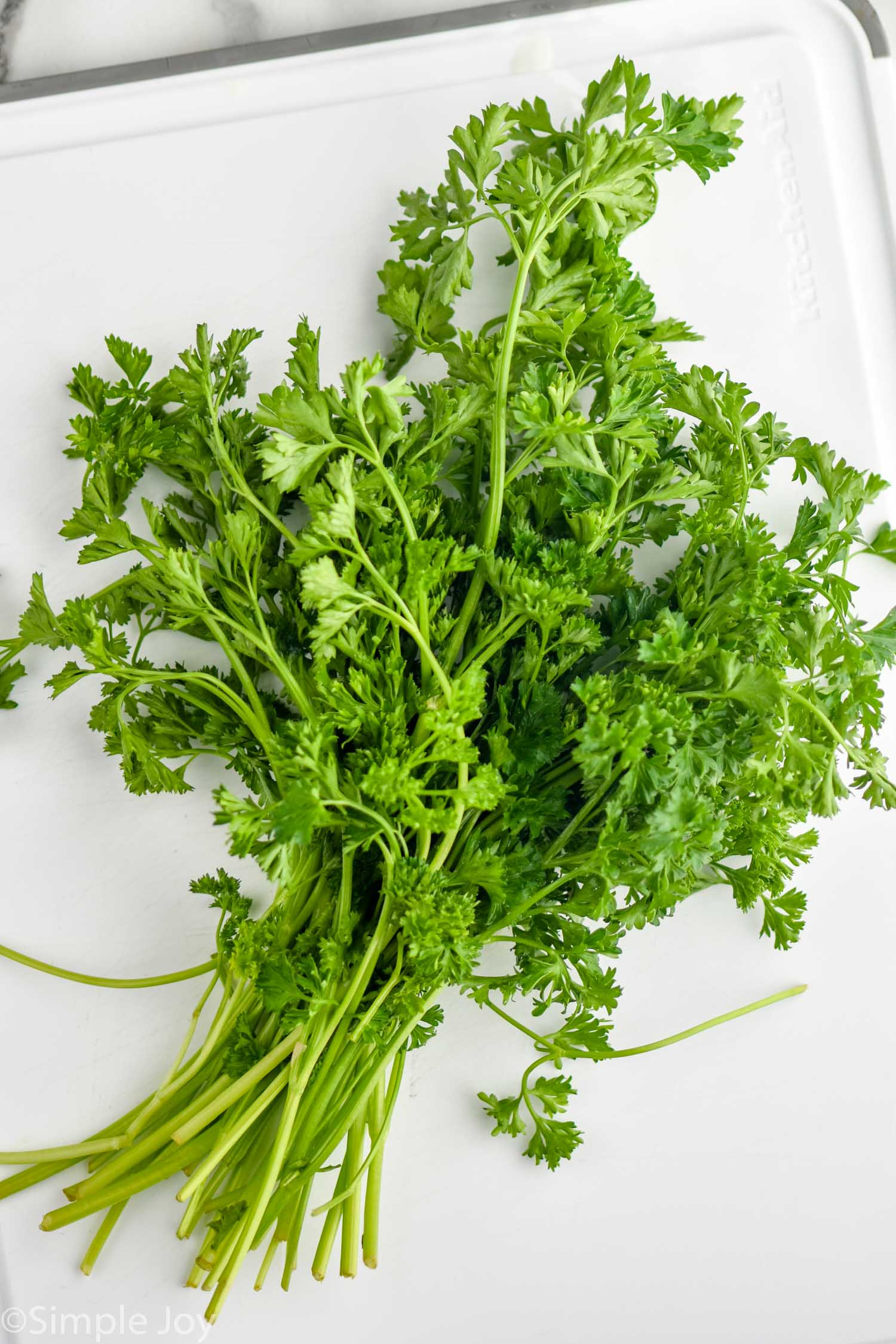 Bunch of fresh parsley on a white cutting board to show How to Store Parsley