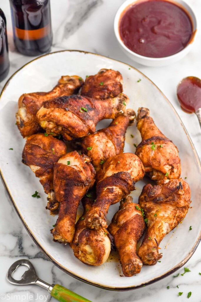 Plate of Oven Baked Chicken Legs with bowl of bbq sauce sitting in background