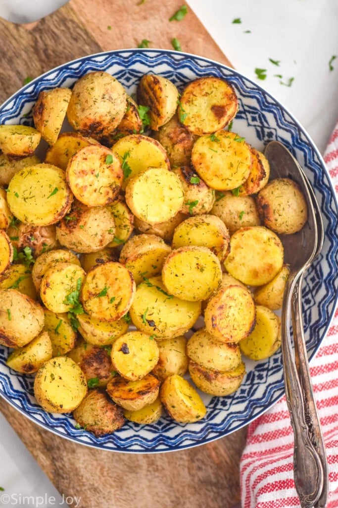 overhead of bowl of Ranch Potatoes topped with fresh parsley with two spoons for serving