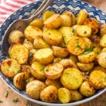 Bowl of Ranch Potatoes topped with fresh parsley with two spoons for serving