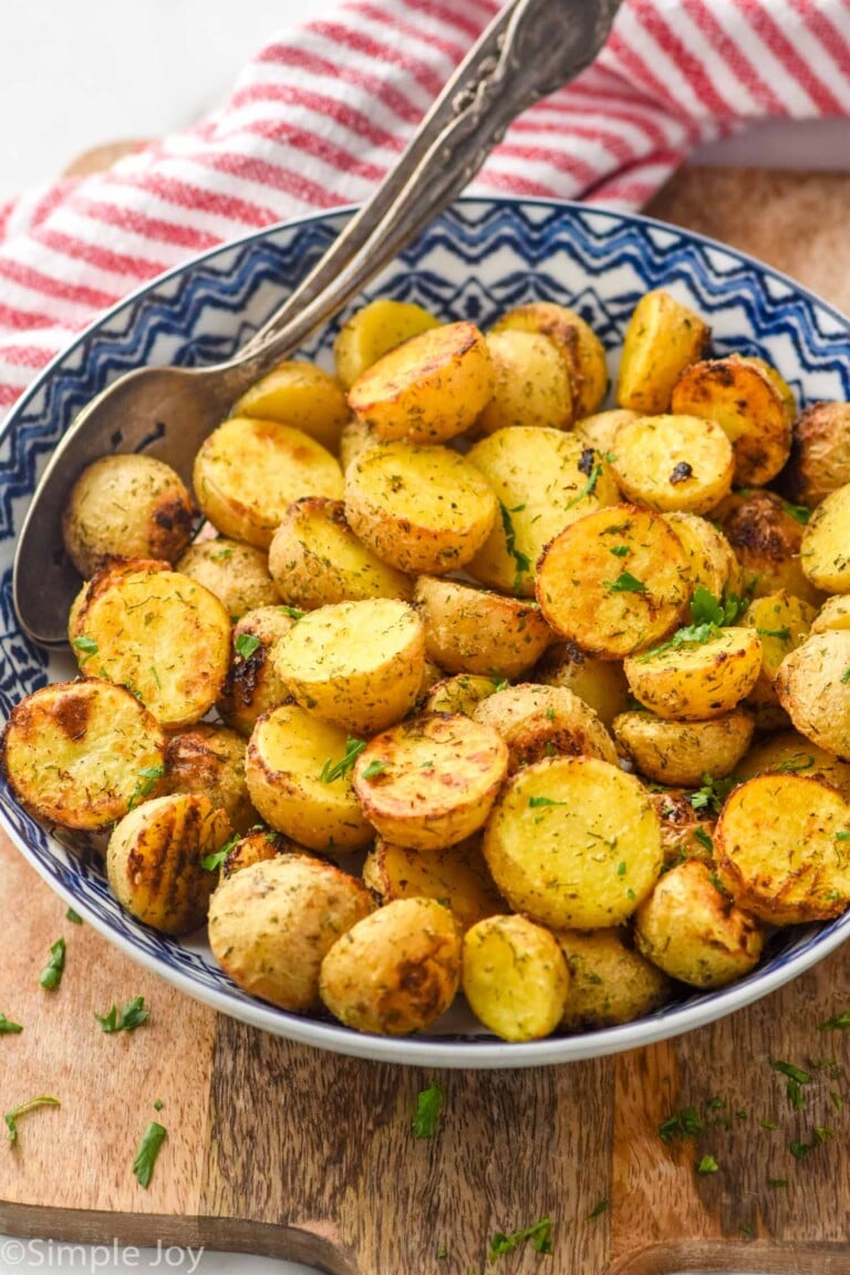 Bowl of Ranch Potatoes topped with fresh parsley with two spoons for serving