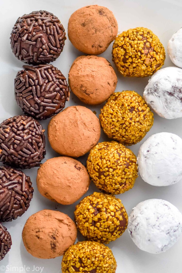 overhead of various chocolate truffles, covered in sprinkles, cocoa powder, gold sprinkles, and powdered sugar