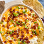 Pinterest graphic for Jalapeño Popper Dip. Says "the best Jalapeño Popper Dip simplejoy.com" Image shows dish of Jalapeño Popper Dip topped with diced bacon and green onion, tortilla chips sitting in dip and surrounding dip