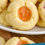 Pinterest graphic for Thumbprint Cookies recipe. Image shows close up of Thumbprint Cookies with two different colors of jam on a plate. Text says, "Tried and tested Thumbprint Cookies simplejoy.com"