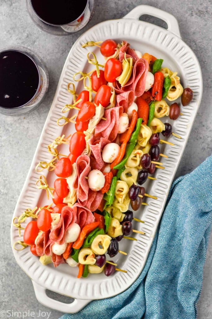 overhead of platter of Antipasto Skewers with two glasses of red wine sitting beside