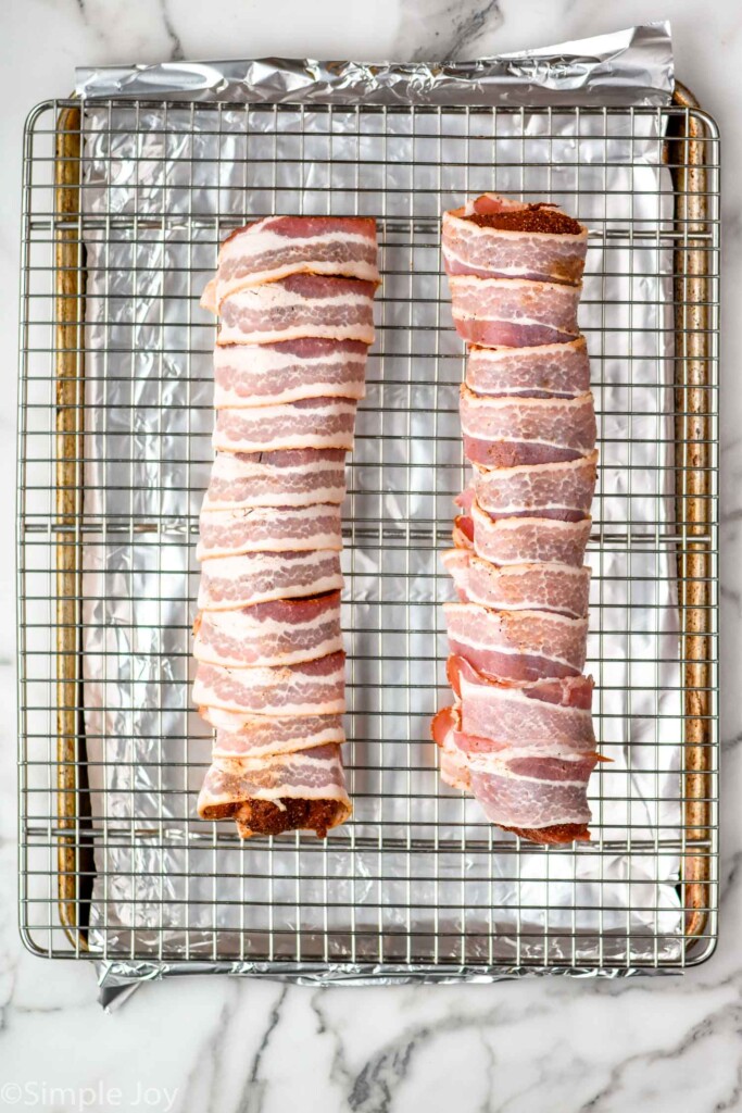 Overhead view of Bacon Wrapped Pork Tenderloin before cooking on wire rack over baking sheet.