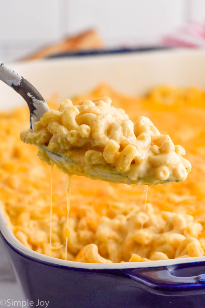 serving spoon dishing up baked Mac and cheese from a casserole dish