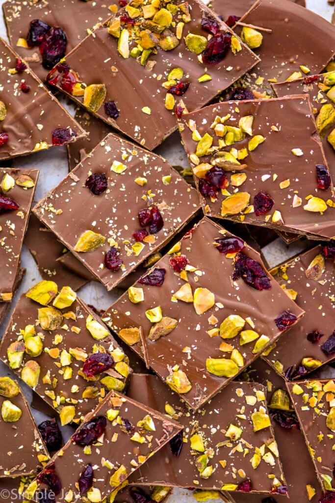 pieces of chocolate bark topped with chopped nuts, dried cranberries, and salt