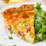 Piece of homemade quiche recipe on a plate with arugula salad