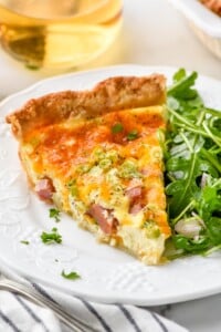 Piece of homemade quiche recipe on a plate with arugula salad