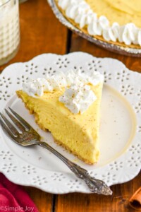 Piece of Eggnog Pie on a plate topped with whipped cream and a fork sitting beside