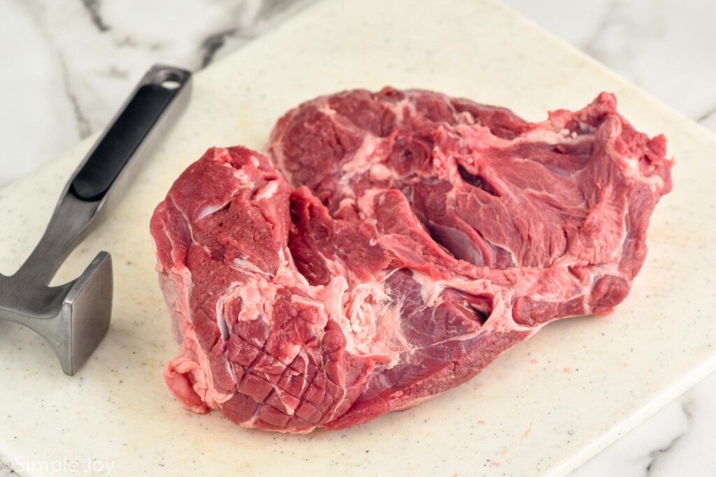 Boneless Leg of Lamb on a cutting board with meat mallet sitting beside