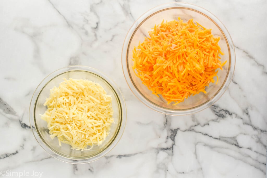 overhead of a bowl of cheddar cheese and a smaller bowl with gruyere