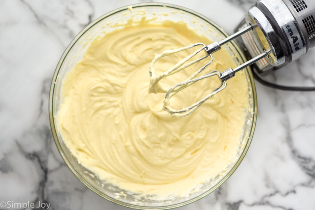 Overhead of bowl of eggnog pie ingredients with hand mixer sitting beside