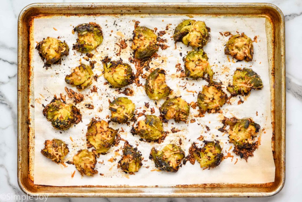 Overhead view of parchment-lined baking sheet of baked Smashed Brussel Sprouts.