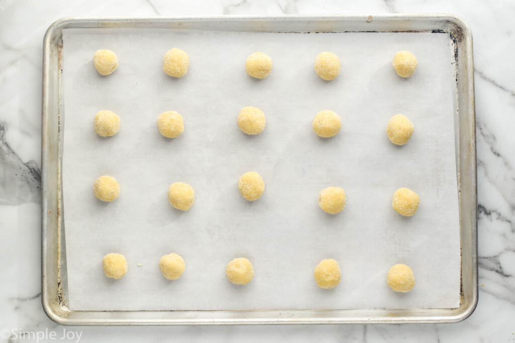 Overhead view of balls of dough on a parchment-lined baking sheet for Thumbprint Cookies recipe.