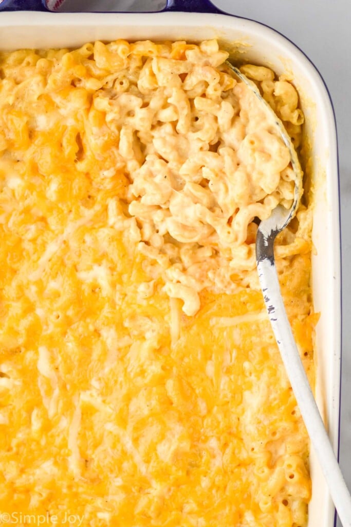 overhead of a serving spoon in a casserole dish of Mac and cheese recipe that has been baked