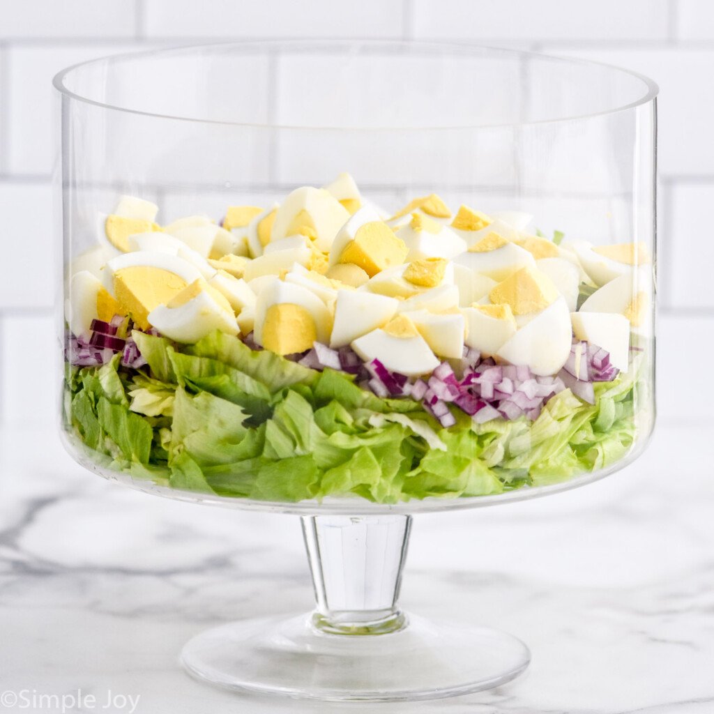 Trifle dish with layered Seven Layer Salad ingredients