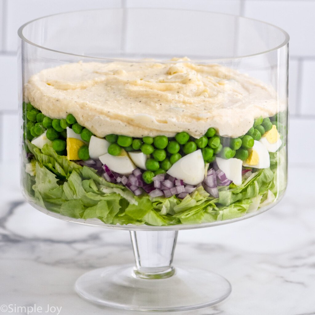 Trifle dish with layered Seven Layer Salad ingredients