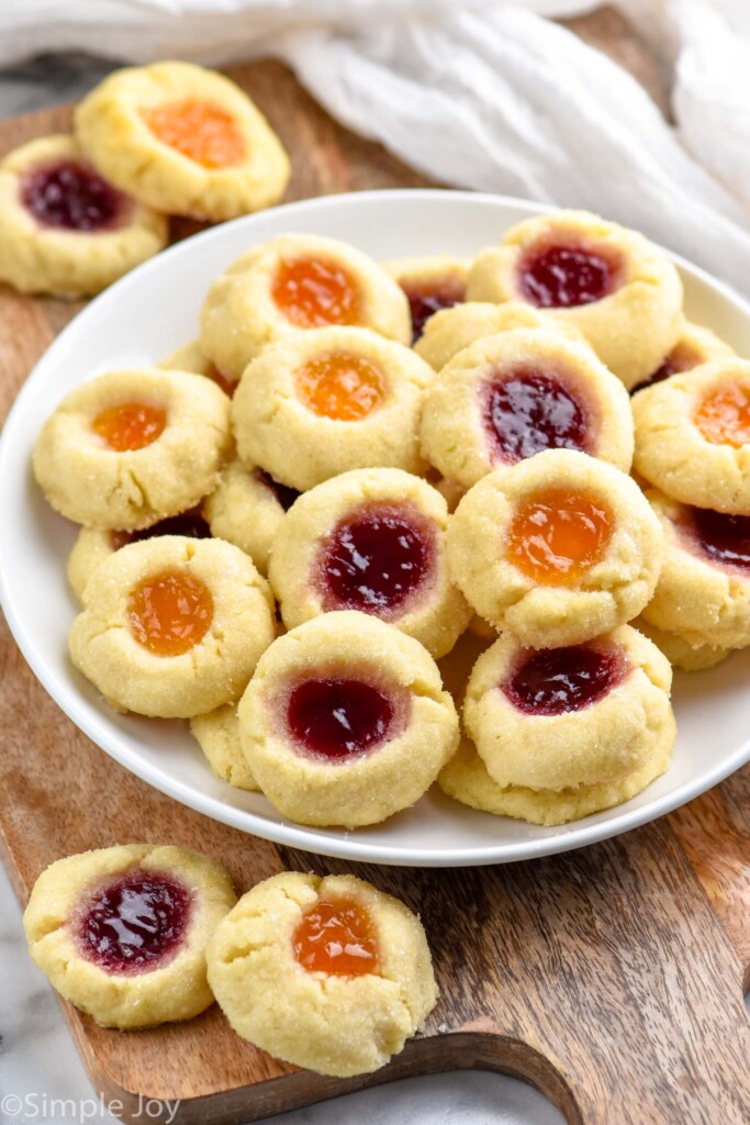 Photo of Thumbprint Cookies with two different colors of jam served on a plate.