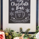 Pinterest graphic for Hot Chocolate Bar. Image shows a framed Hot Chocolate Bar sign that says "hot chocolate bar warm up buttercup" Text says "the best Hot Chocolate Bar sign simplejoy.com"