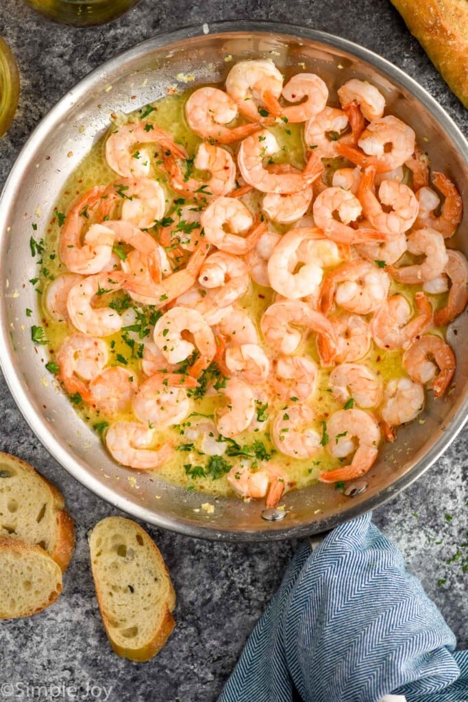 overhead of skillet of Garlic butter shrimp topped with fresh parsley