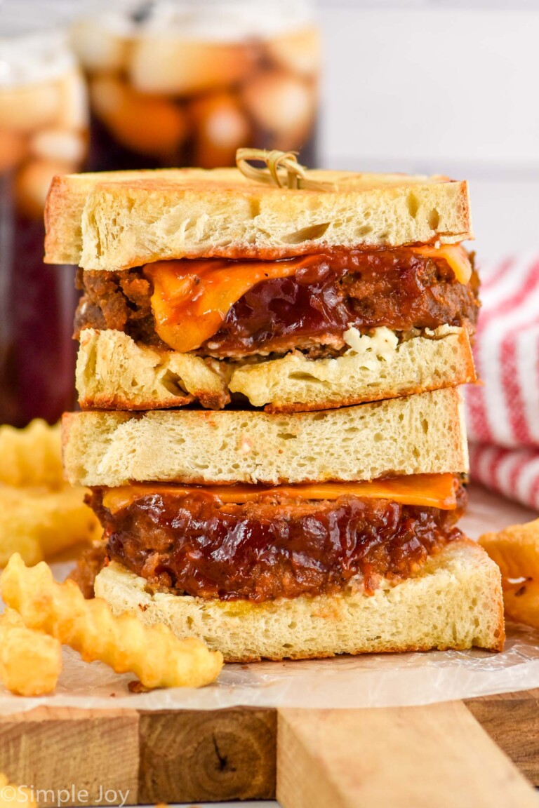 two meatloaf sandwiches on top of each other with french fries sitting beside